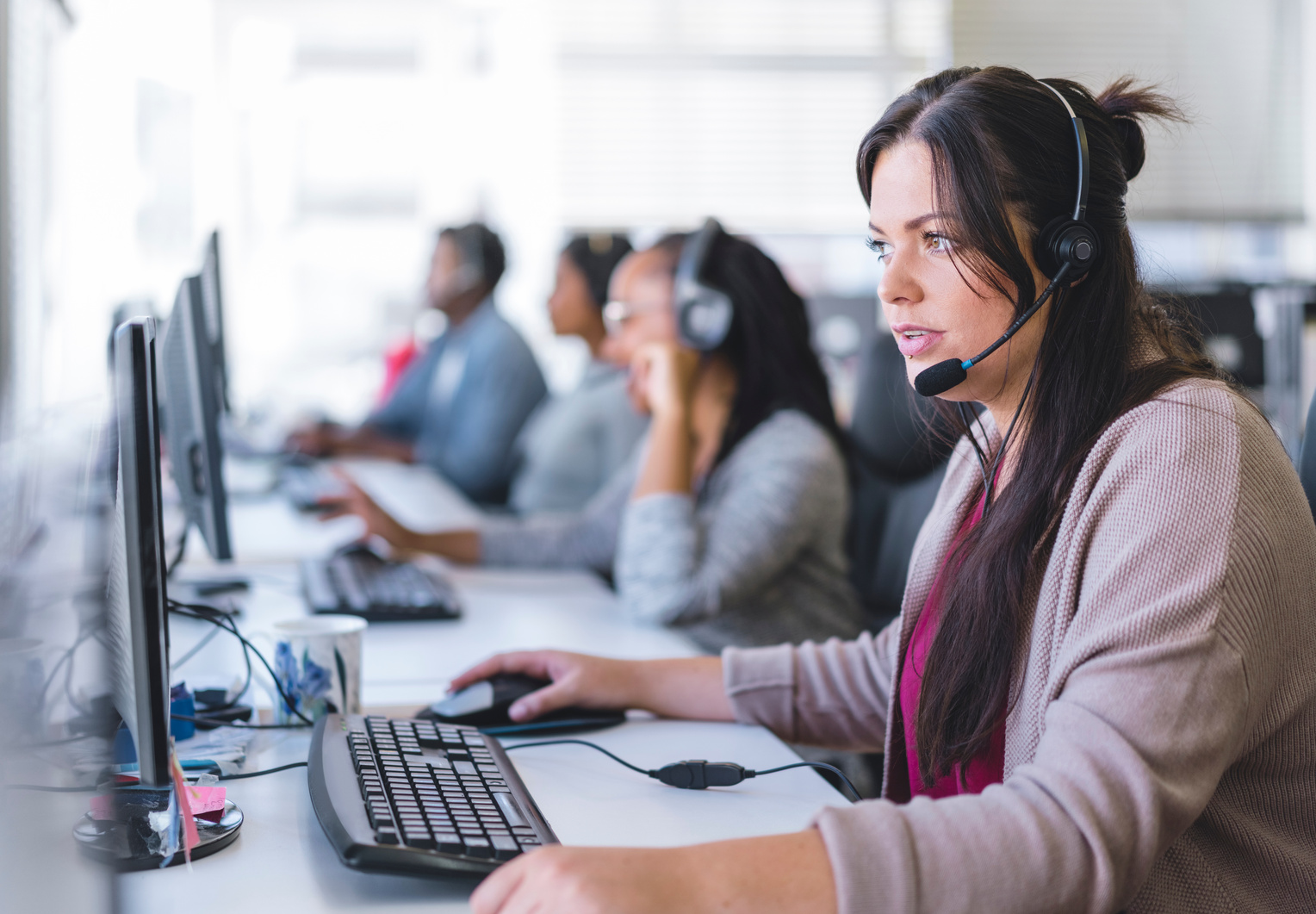 Telemarketer using headset and computer at desk